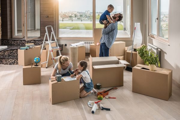 Young happy family moved into a new penthouse. Father is playing with son, while mother and daughter are talking.